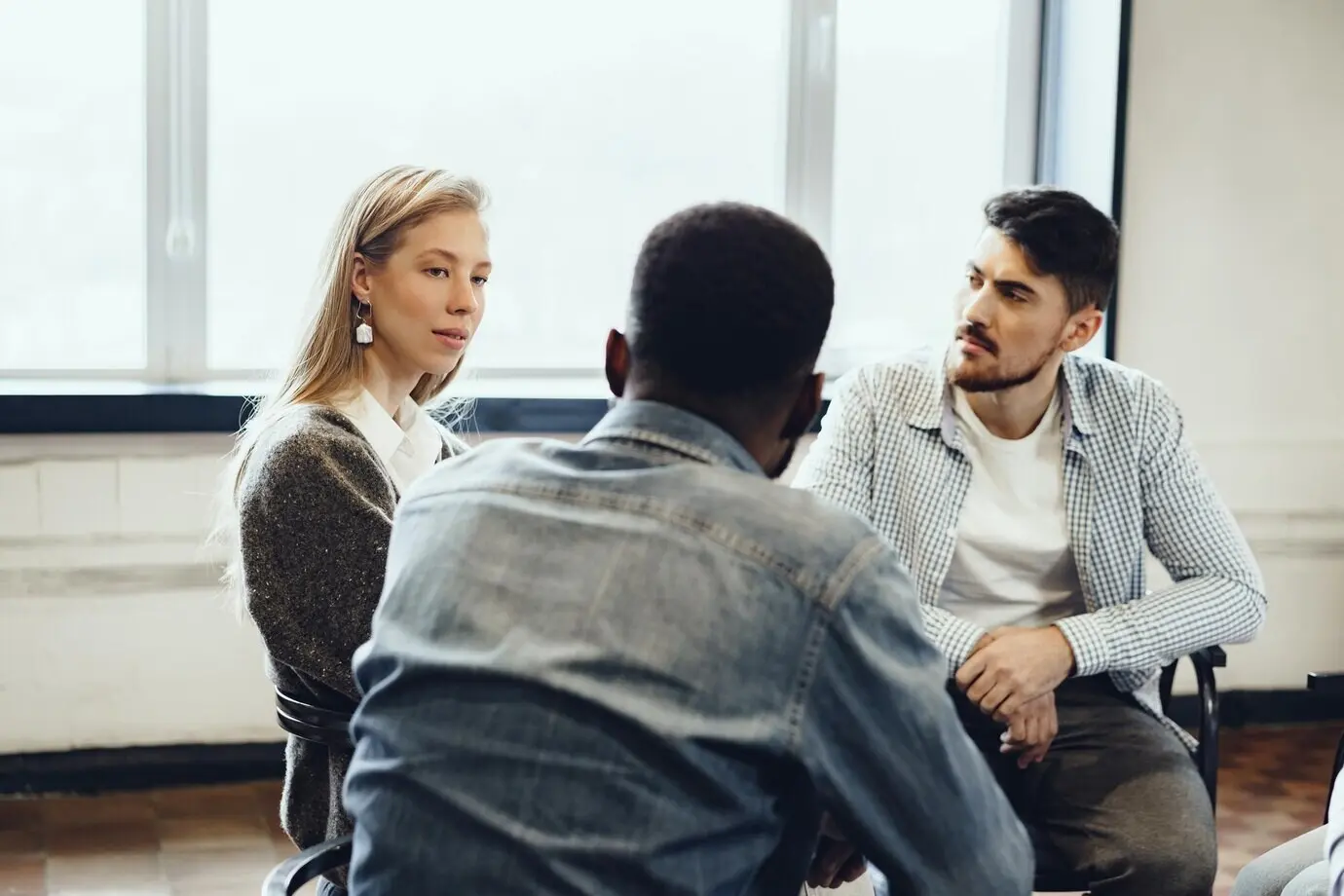 Young people are seated in a circle, engaged in a discussion.