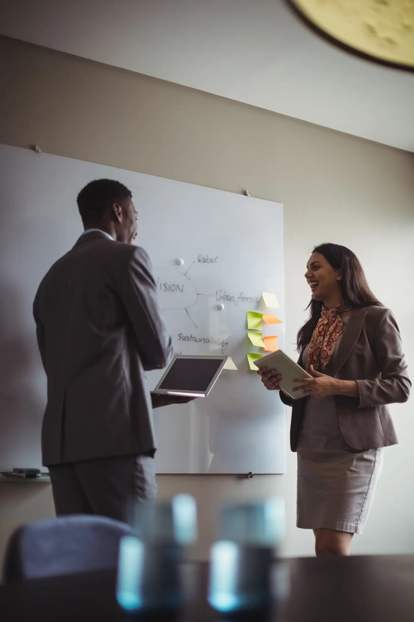 A businessman discusses with a colleague at a whiteboard.