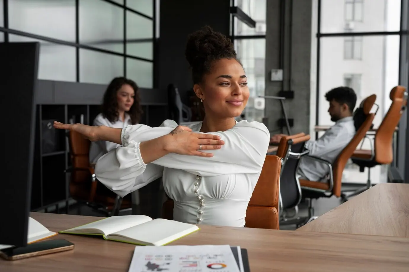 A medium shot of a woman stretching at work.